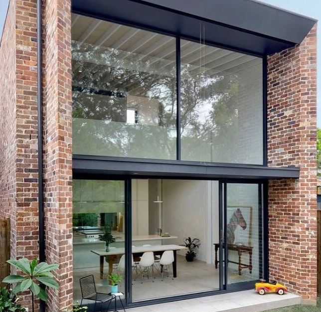Casa com parede de vidro integrando cozinha e jardim